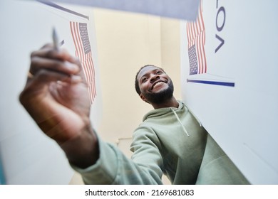 Low Angle Portrait Of Black Young Man Putting Ballot In Voting Bin, Out Of Box View