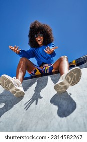 Low angle portrait happy young woman gesturing and laughing at edge of sunny sports ramp - Shutterstock ID 2314582267