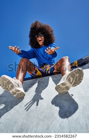 Low angle portrait happy young woman gesturing and laughing at edge of sunny sports ramp