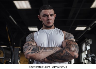 Low Angle Portrait Of A Strong Muscular Tattooed Bodybuilder Looking To The Camera Powerfully