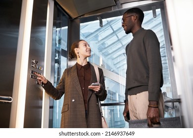 Low angle portrait of two young coworkers chatting in glass elevator at modern office building - Powered by Shutterstock