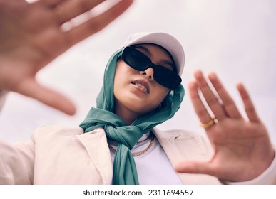 Low angle portrait, woman and city for muslim fashion with gen z aesthetic, streetwear and sky background. Young islamic girl, student and clothes with sunglasses, freedom and outdoor travel in Dubai