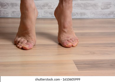 Low angle POV of man's bare feet standing at home sticks on the tips of his fingers at home