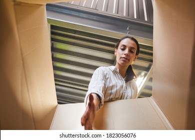 Low Angle POV Shot At Young Woman Reaching Into Box While Loading Self Storage Unit, Copy Space