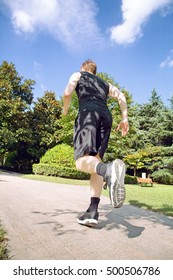 Low Angle Rear View Of Caucasian Man Running In Park