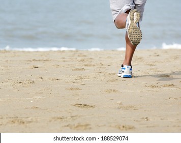 Low angle rear view of young man jogging at the beach 