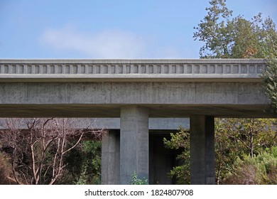 Low angle sectional view of two parallel concrete freeway bridges, one for each direction