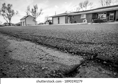 low angle selective focus on asphalt overlay paving on top of a concrete base of a residential street
