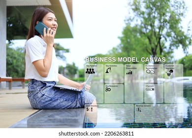 Low Angle Shot Of Asian Woman Talking With Smartphone And Laptop In Hand Sitting By The Pool. Business Model Canvas Concept.