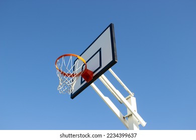 Low angle shot of basketball hoop on sunny day outside at basketball court in city park. Basketball basket with white backboard against blue cloudless sky. Achievement, sports concept - Powered by Shutterstock