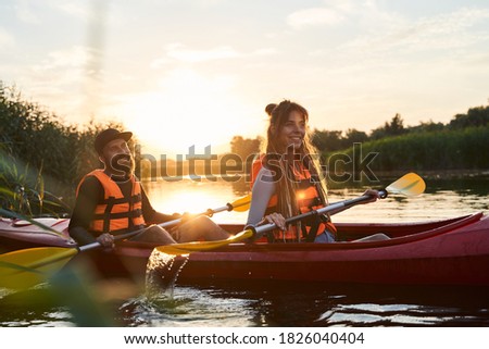 Low angle shot of beautiful couple kayaking on river together at sunset