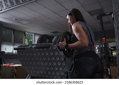 Low Angle Shot Of A Female Bodybuilder Putting Weights On Leg Press Machine