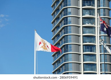 Low angle shot of flags fluttering against a blue sky and contemporary high-rise apartment building.