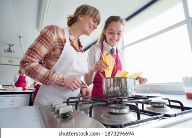 Low Angle Shot Of A High School Girl And Her Teacher Cooking Pasta During A Home Economics Class.