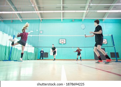 Low Angle Shot Of High School Students Playing Badminton During A Gym Class.