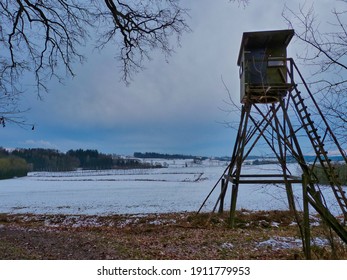 A Low Angle Shot Of A Hunting Tower Near A Snow-covered Field