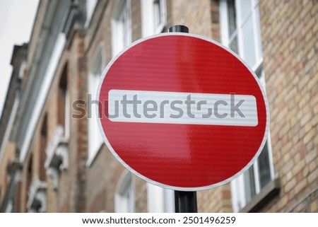A low angle shot looking up at an isolated no entry sign with blurred building background 