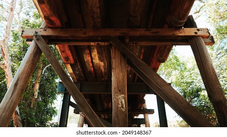 Low Angle Shot Looking Up At A Wooden Bridge That Runs Over A Creek