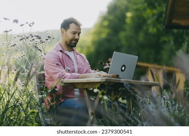 Low angle shot of man working outdoors in the garden, with laptop on legs. Businessman working remotely from homeoffice, thinking about new business or creative idea. - Powered by Shutterstock