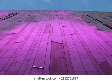 A Low Angle Shot Of A Modern Abstract Building With Purple And Pink Neon Light Cast On Its Side