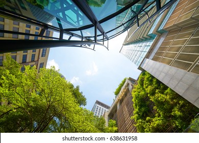 Low angle shot of modern glass buildings and green with clear sky background. - Powered by Shutterstock
