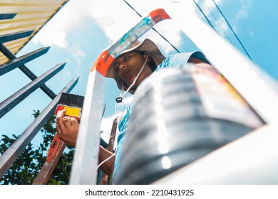 Low Angle Shot Of A Nicaraguan Woman On A Ladder Painting A Fence