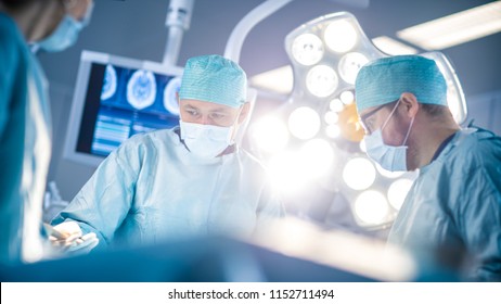 Low Angle Shot in the Operating Room, Assistant Hands out Instruments to Surgeons During Operation. Surgeons Perform Operation. Professional Medical Doctors Performing Surgery.