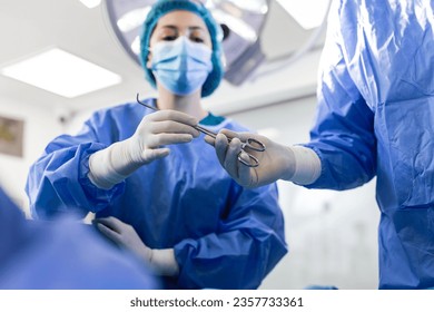 Low Angle Shot in the Operating Room, Assistant Hands out Instruments to Surgeons During Operation. Surgeons Perform Operation. Professional Medical Doctors Performing Surgery. - Powered by Shutterstock