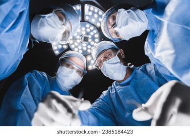 Low angle shot in operating room. Professional medical doctors performing surgery. Surgeons medical workers doctors looking at the patient on operating table in hospital surgery theater - Powered by Shutterstock