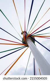 A low angle shot of a pole with colored ribbons on a traditional English Maypole dancing day
