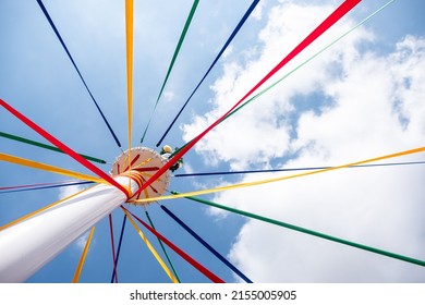 A low angle shot of a pole with colored ribbons on a traditional English Maypole dancing day