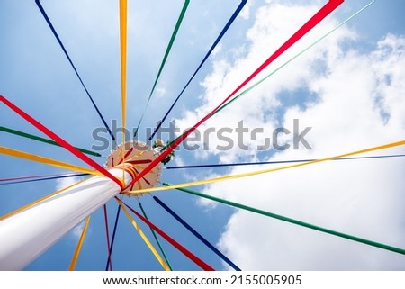 A low angle shot of a pole with colored ribbons on a traditional English Maypole dancing day