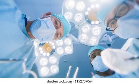 Low Angle Shot POV Patient View: Two Professional Surgeons Holding Surgical Instruments Starting Surgery.
