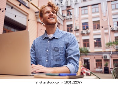 Low Angle Shot Of Red Head Man Sitting On Table With Laptop