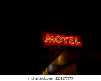 A low angle shot of red neon motel sign against black sky background