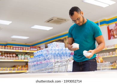 Low Angle Shot Of Smiling Man Holding Products From Freezer. Handsome Bearded Guy Shopping In Grocery Store. Shopping Concept