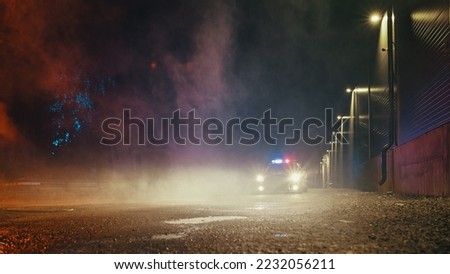 Low Angle Shot of a Stopped Police Car with Lights and Siren on During a Misty Night. Patrolling Vehicle on Stand by, Waiting for Orders to Start Pursuing Suspects. Police Enforcement