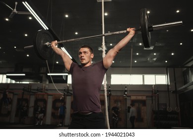 Low angle shot of a strong muscular athlete lifting heavy barbell overhead - Powered by Shutterstock