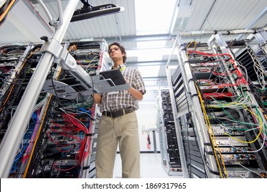 Low angle shot of a technician working on a computer in a server room at a data center.
