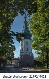 A Low Angle Shot Of The Tower Of Town Hall With A Spire In Front Of An Empty Road Against The Sky By Summer Day