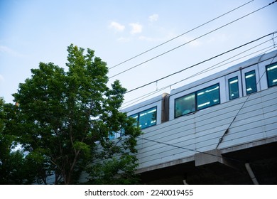 A low angle shot of a train driving in the city on a sunny day