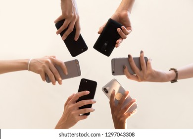 Low angle shot of women hands holding smartphones making picture or shooting video, female stand in circle using mobile phones, technology addicted girls connect to wireless network with cellphone