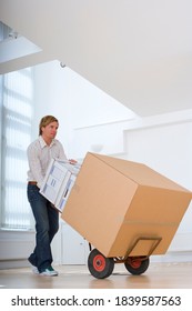 Low Angle Shot Of A Young Man Moving Boxes Using A Hand Trolley Indoors.