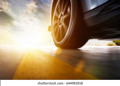 Low Angle Side View Of Car Driving Fast At Sunset With Motion Speed Effect .