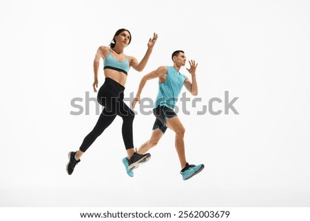 Low angle side view dynamic image of young athletic woman and muscular man in motion, training, running against white studio background. Sport, active and healthy lifestyle, workout, fitness concept