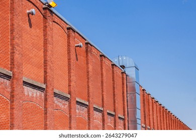 Low angle side view of old industrial building red brick wall against bright blue sky, Sherbrooke, Quebec, Canada