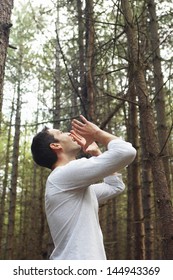 Low Angle Side View Of A Young Man Standing Alone In Woods And Yelling