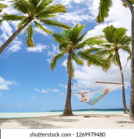 LOW ANGLE: Sleeping Caucasian woman sways in a rope hammock on the spectacular tropical white sand beach in Cook Islands. Relaxed female tourist enjoying her summer vacation by taking a nap by ocean. - Powered by Shutterstock