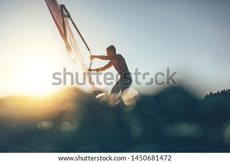 Low angle splashing view of windsurfer sailing on windsurf board. Windsurfer sailing on the surf board Foto d'archivio © 