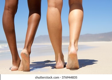 Low angle two women walking barefoot on beach 